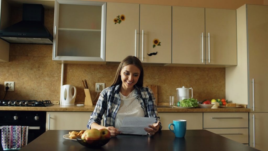 Attractive happy woman recieve good news reading letter in the kitchen while have breakfast at home